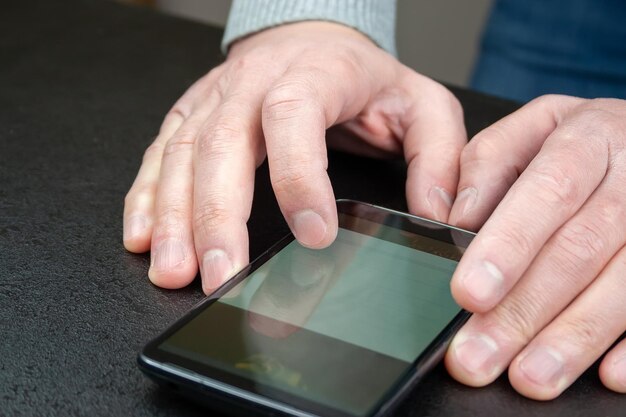 Homem lê notícias em seu celular que está sobre a mesa