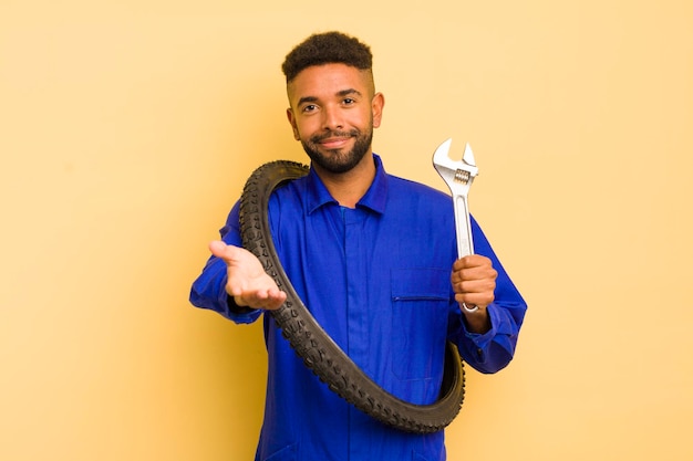 Homem legal afro sorrindo alegremente com amigável e oferecendo e mostrando um conceito conceito de reparador de bicicletas