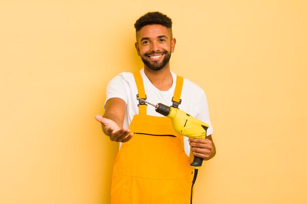 Homem legal afro sorrindo alegremente com amigável e oferecendo e mostrando um conceito de faz-tudo e conceito de broca