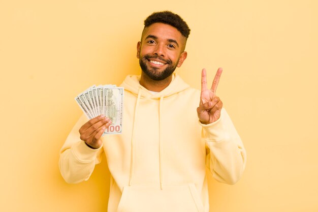 Foto homem legal afro sorrindo e parecendo amigável mostrando o conceito de notas de dois dólares