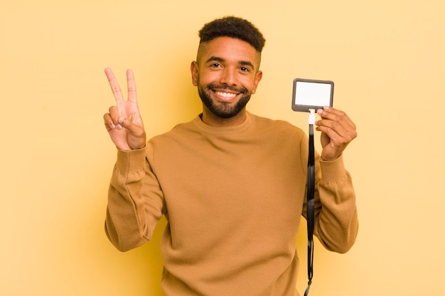 Homem legal afro sorrindo e parecendo feliz gesticulando vitória ou conceito de identificação de passe vip de paz