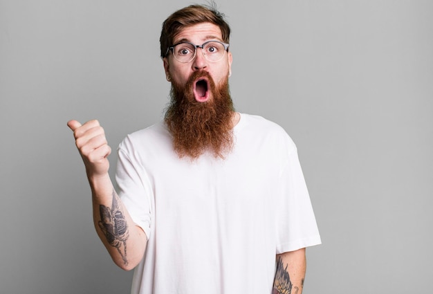 Homem legal de barba longa e cabelo ruivo vestindo uma camisa simples e com um espaço de cópia