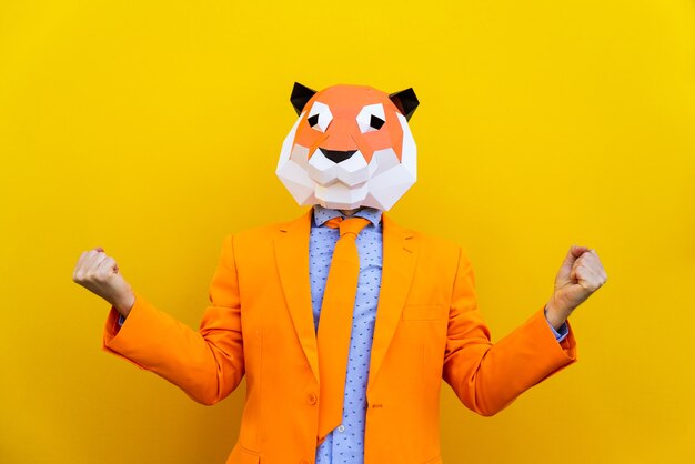 Homem legal usando máscara de origami 3d com roupas coloridas elegantes - conceito criativo para publicidade, máscara de cabeça de animal fazendo coisas engraçadas em fundo colorido