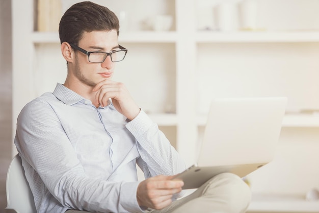 Homem lendo algo na tela do laptop