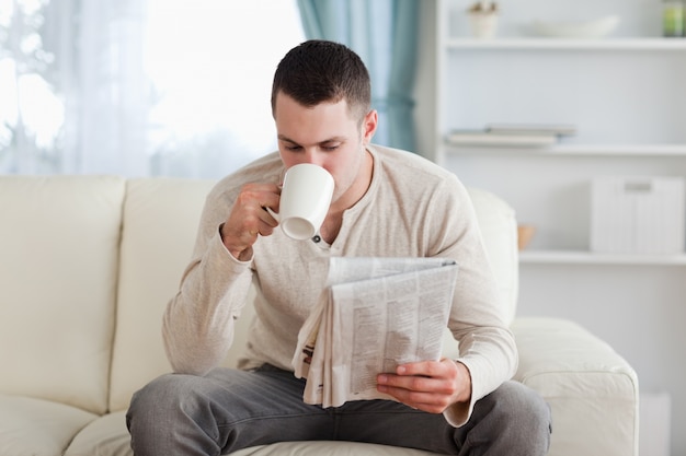 Homem lendo as notícias enquanto toma um chá