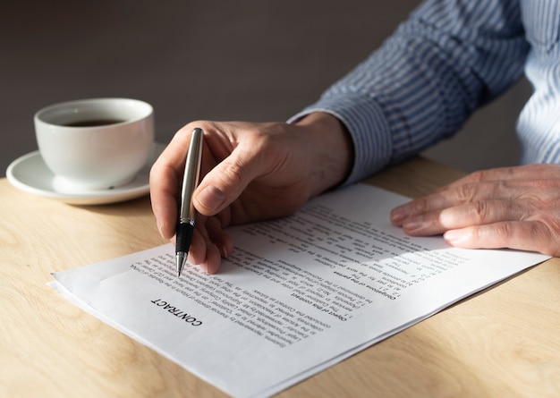 Homem lendo contrato para assiná-lo na mesa do escritório.