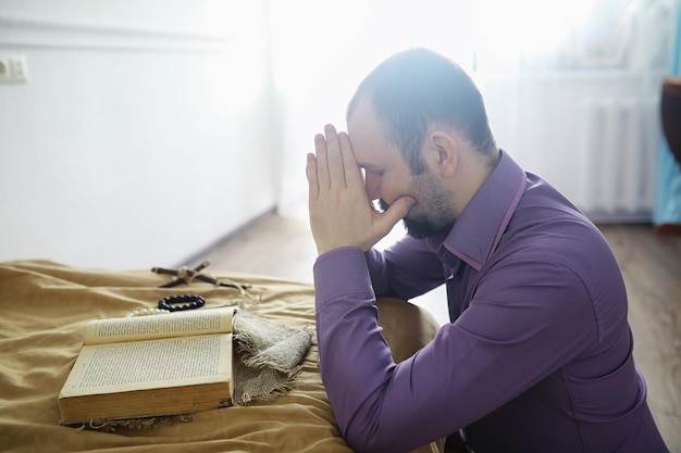 Foto homem lendo e orando da bíblia sagrada perto da cama à noite cristãos e conceito de estudo bíblico estudando a palavra de deus na igreja