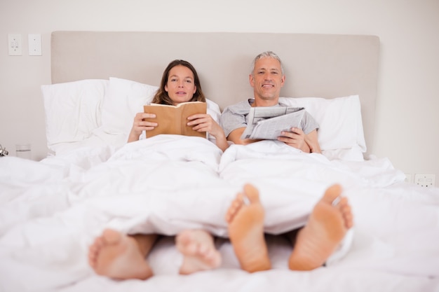 Homem lendo um jornal enquanto sua esposa está lendo um livro