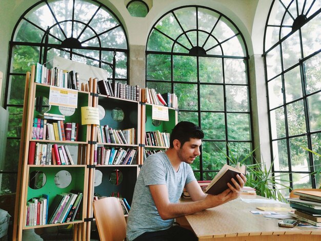 Foto homem lendo um livro na biblioteca