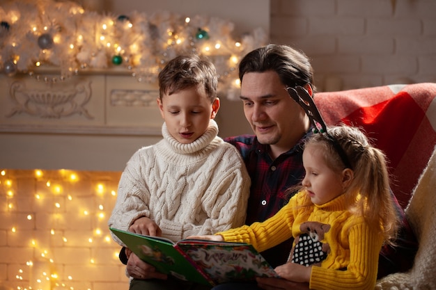 Homem lendo um livro para um menino e uma menina