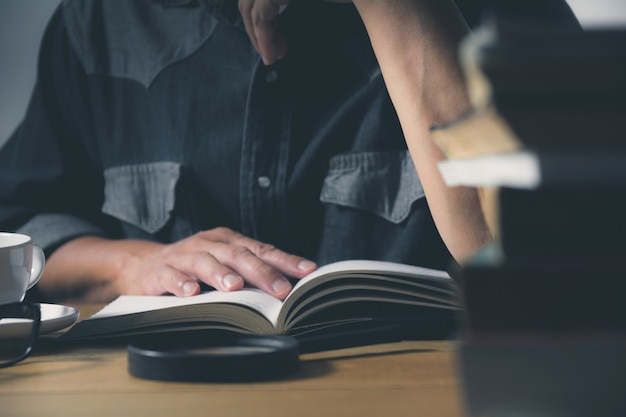 Homem lendo um livro sobre a mesa. Conceito de educação e pessoas.