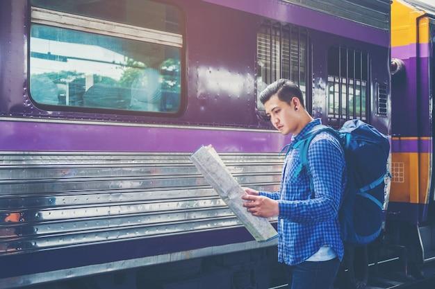 Homem lendo um mapa enquanto está de pé na plataforma da estação ferroviária