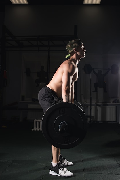 Homem levantando pesos. treino de homem musculoso no ginásio fazendo exercícios com barra