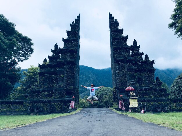 Foto homem levitando sobre a estrada contra as antigas ruínas do templo