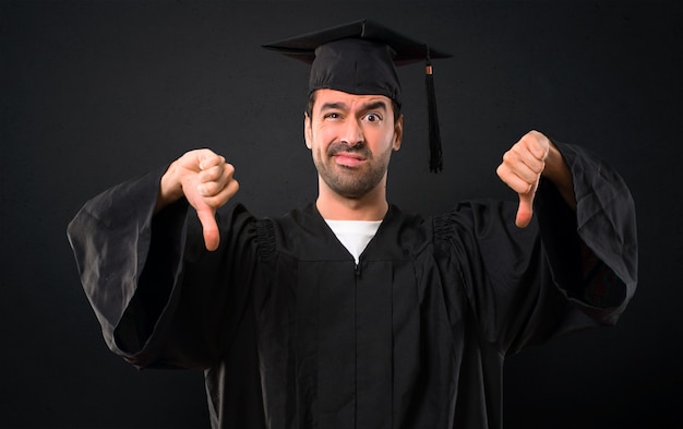 Homem, ligado, seu, dia graduação, universidade, mostrando, polegar baixo, com, ambos, mãos