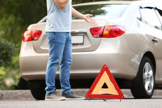 Homem ligando para seu corretor de seguros perto de um carro quebrado na estrada