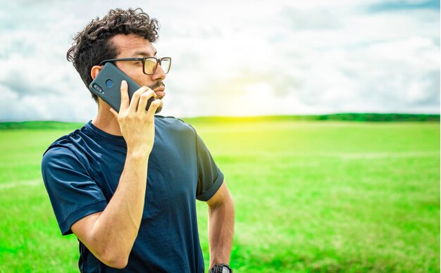 Homem ligando pelo celular jovem no campo ligando pelo celular