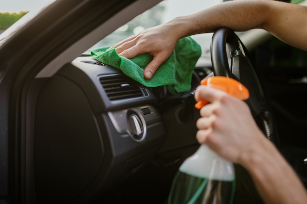 Homem limpa o interior do carro com um pano, estação de lavagem automática de mãos. Indústria ou negócio de lavagem de carros. Indivíduo do sexo masculino limpa seu veículo de sujeira ao ar livre