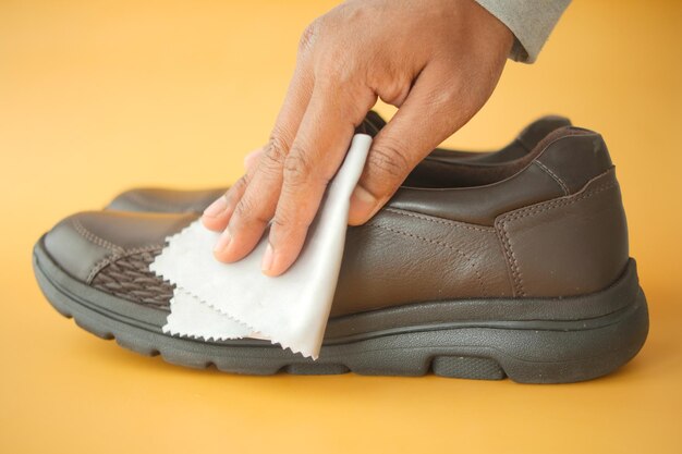 Foto homem limpa seus sapatos de couro com um pano molhado