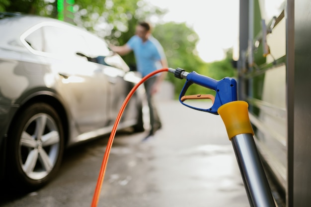 Homem limpa um carro com pano, estação de lavagem automática de mãos