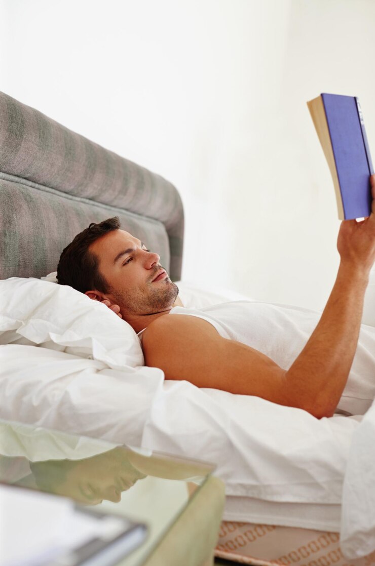 Foto homem livro e leitura na cama para relaxar fantasia e conhecimento de manhã ou fim de semana jornalista homem confortável e aconchegante com literatura e ficção para criatividade e pesquisa para romance em casa