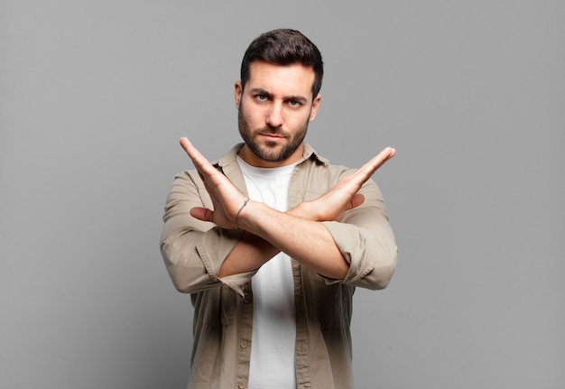 Homem loiro adulto bonito parecendo irritado e cansado de sua atitude, dizendo o suficiente! mãos cruzadas na frente, dizendo para você parar