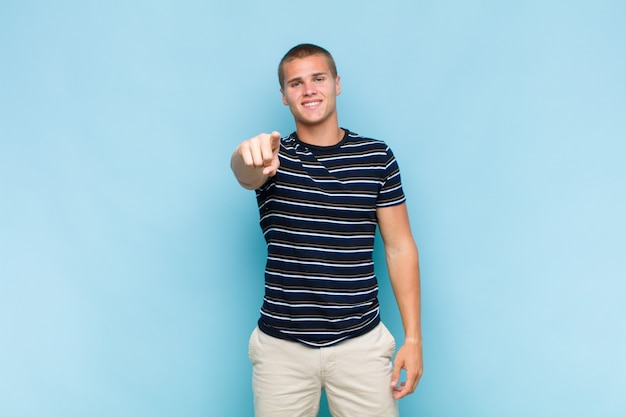 Homem loiro apontando para a frente com um sorriso satisfeito, confiante e amigável, escolhendo você