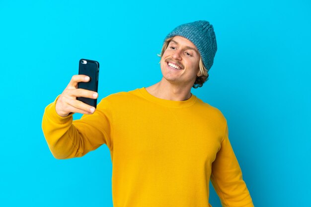 Homem loiro bonito em azul fazendo uma selfie