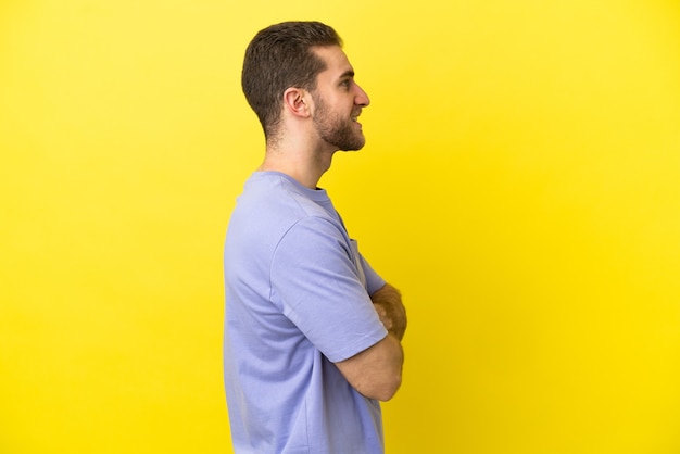 Homem loiro bonito sobre fundo amarelo isolado na posição lateral