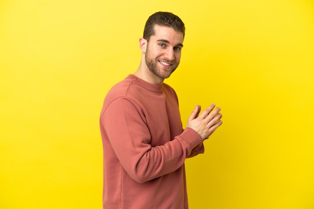 Homem loiro bonito sobre fundo amarelo isolado tramando algo