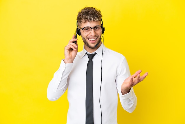 Homem loiro de telemarketing trabalhando com um fone de ouvido isolado em um fundo amarelo, mantendo uma conversa com alguém ao telefone celular