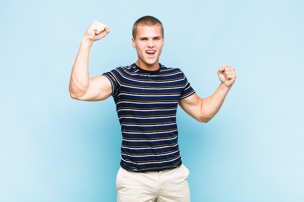 Homem loiro gritando triunfantemente, parecendo um vencedor animado, feliz e surpreso, comemorando