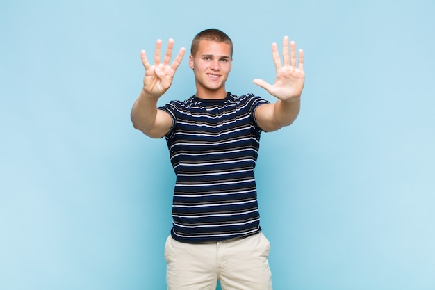 Homem loiro sorrindo e parecendo amigável, mostrando o número nove ou nono com a mão para a frente, em contagem regressiva