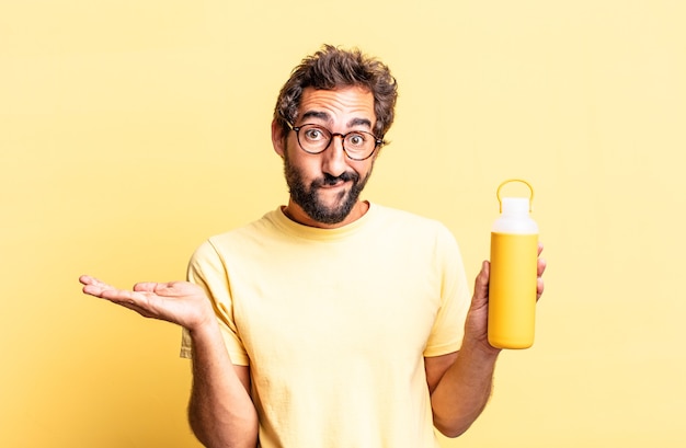 homem louco expressivo se sentindo perplexo e confuso e duvidando de uma garrafa térmica de chá