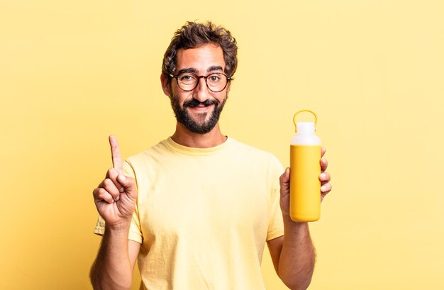 Homem louco expressivo sorrindo e parecendo amigável, mostrando o número um com uma garrafa térmica de chá