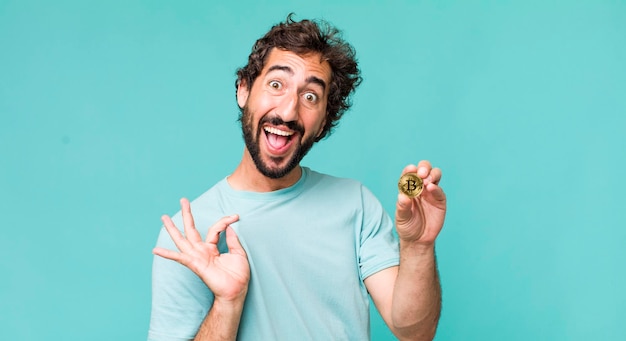 Homem louco latino-americano adulto jovem com uma moeda bitcoin