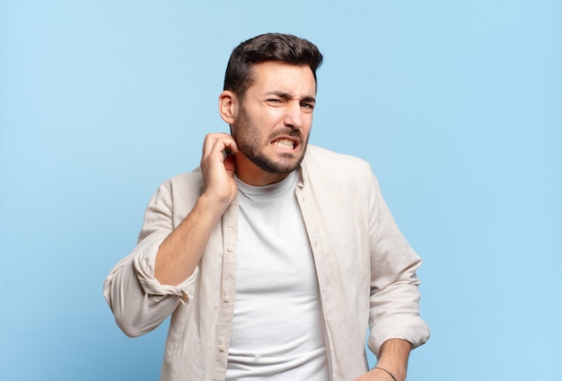 Homem louro adulto bonito se sentindo estressado, frustrado e cansado, esfregando o pescoço dolorido, com um olhar preocupado e preocupado