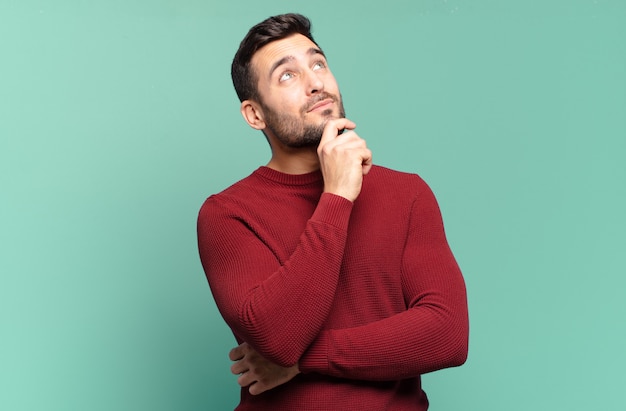 Homem louro adulto bonito se sentindo pensativo, pensando ou imaginando ideias, sonhando acordado e olhando para cima para copiar o espaço