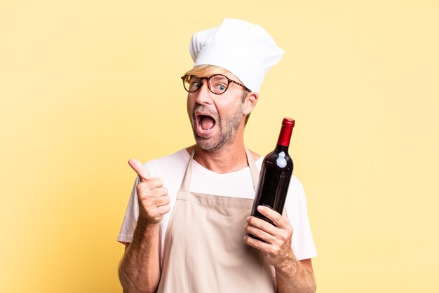 Homem louro bonito chef adulto segurando uma garrafa de vinho