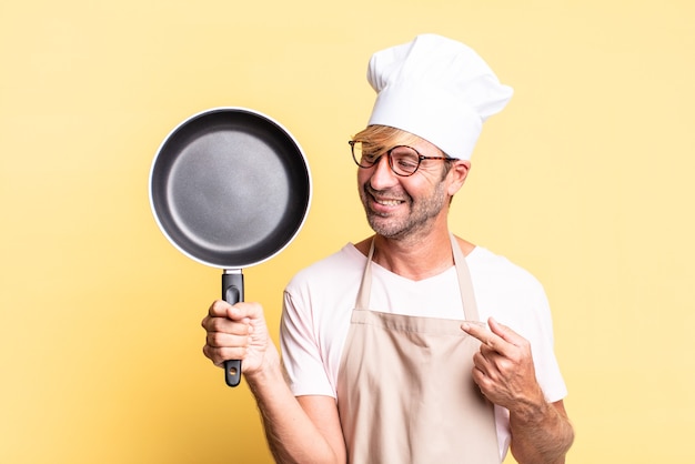 Homem louro e bonito chef adulto segurando uma panela