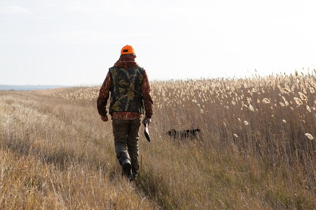 Foto homem maduro caçador com arma enquanto caminha no campo