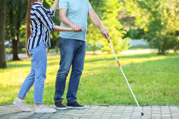 Homem maduro cego com filha caminhando no parque