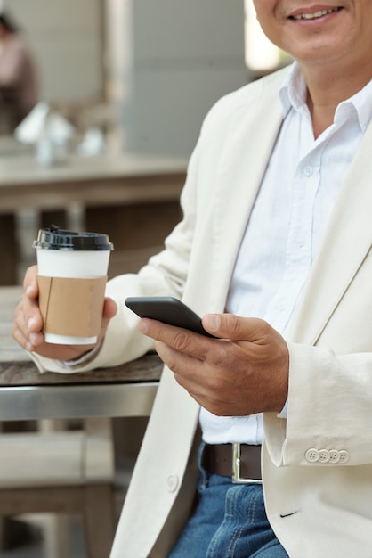 Homem maduro com gadget no café de rua