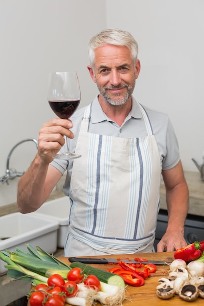 Homem maduro, com, vidro vinho, enquanto, legumes chopping, em, cozinha
