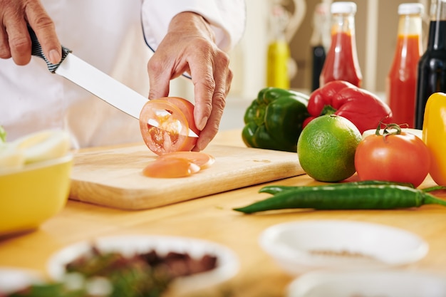 Homem maduro cortando tomate