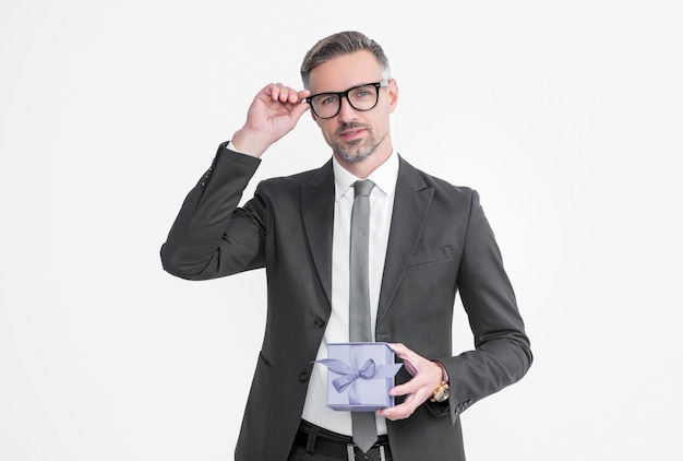 Homem maduro de óculos e terno segura caixa de presente isolada no fundo branco