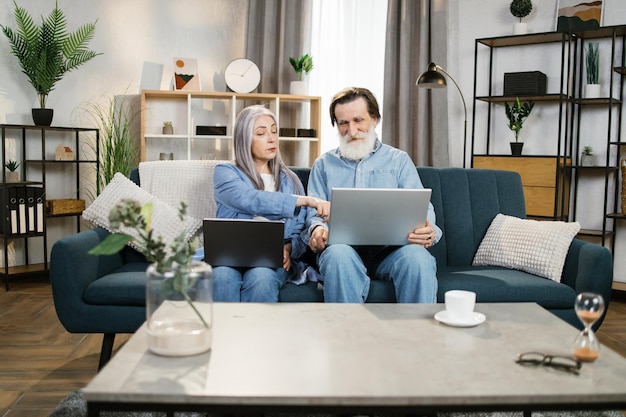 Homem maduro e mulher usando laptops olhando para a tela