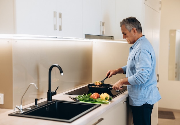 Homem maduro preparando comida saudável para o jantar de sua família