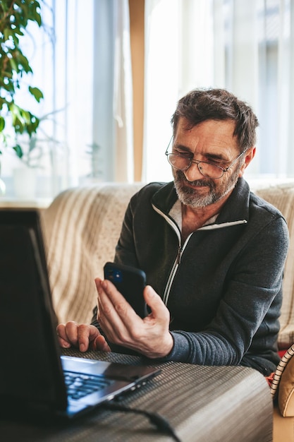 Homem maduro sorridente usando smartphone