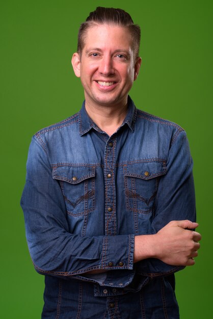 Homem maduro, vestindo camisa jeans contra fundo verde